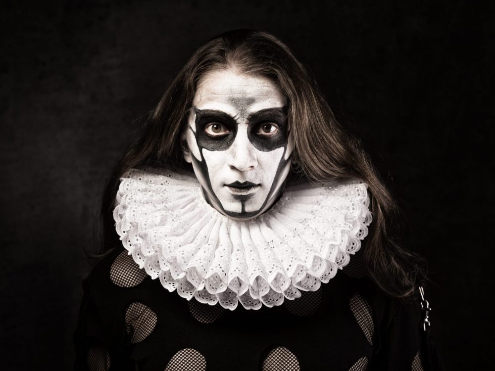 Portrait of man in goth style clothes and  ruff collar with scull makeup.